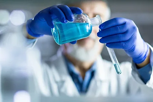 A chemist pouring a blue solution between vessels